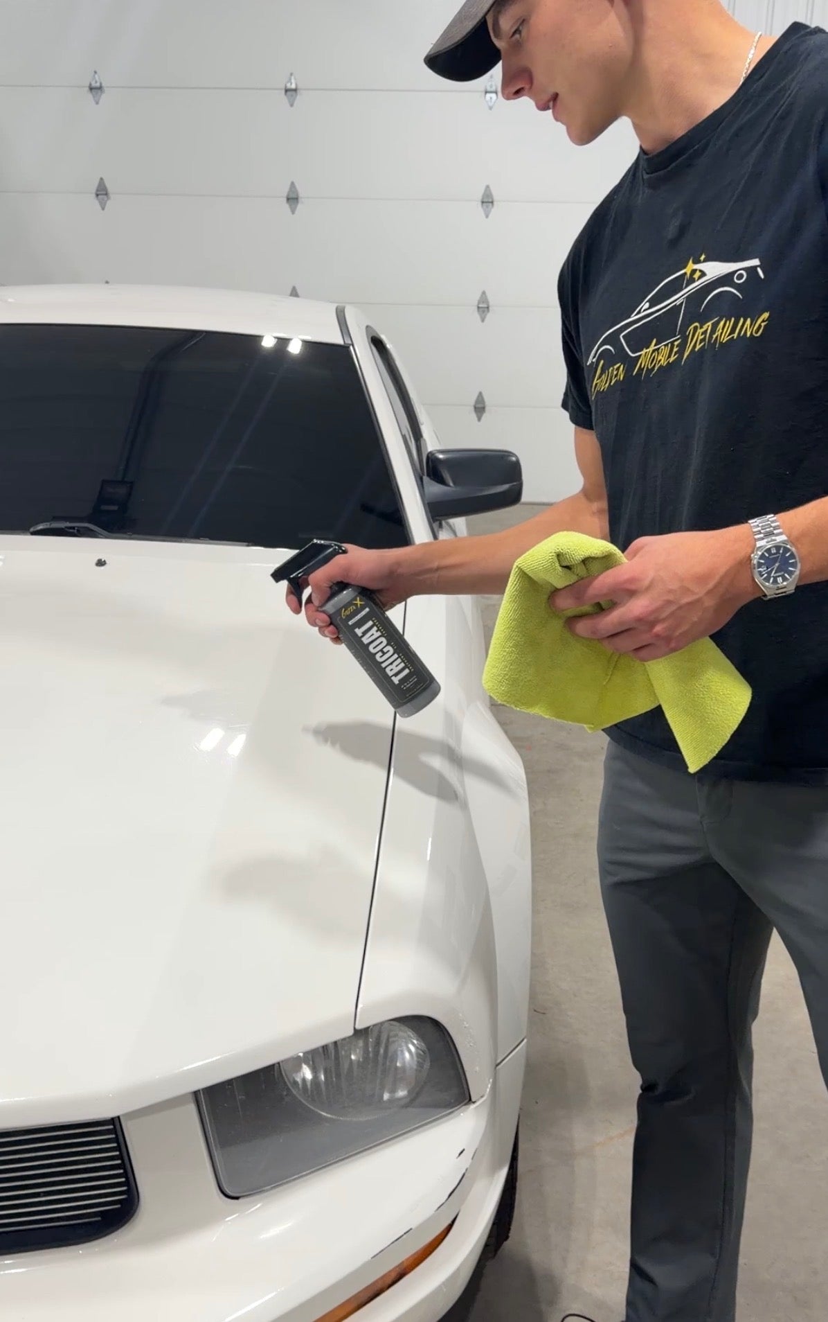 Golden Mobile Detailing technician applying GoldenX Tricoat spray wax to a white car with a microfiber towel